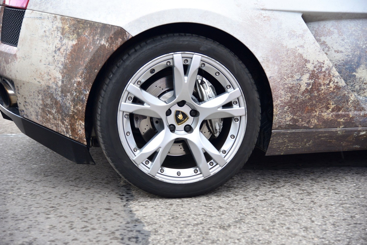 Close-up of Lamborghini alloy wheel and brake disc with textured body panel