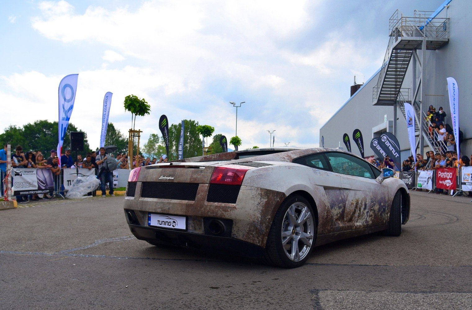 Rear view of a dirt-covered Lamborghini Gallardo Coupe at an event