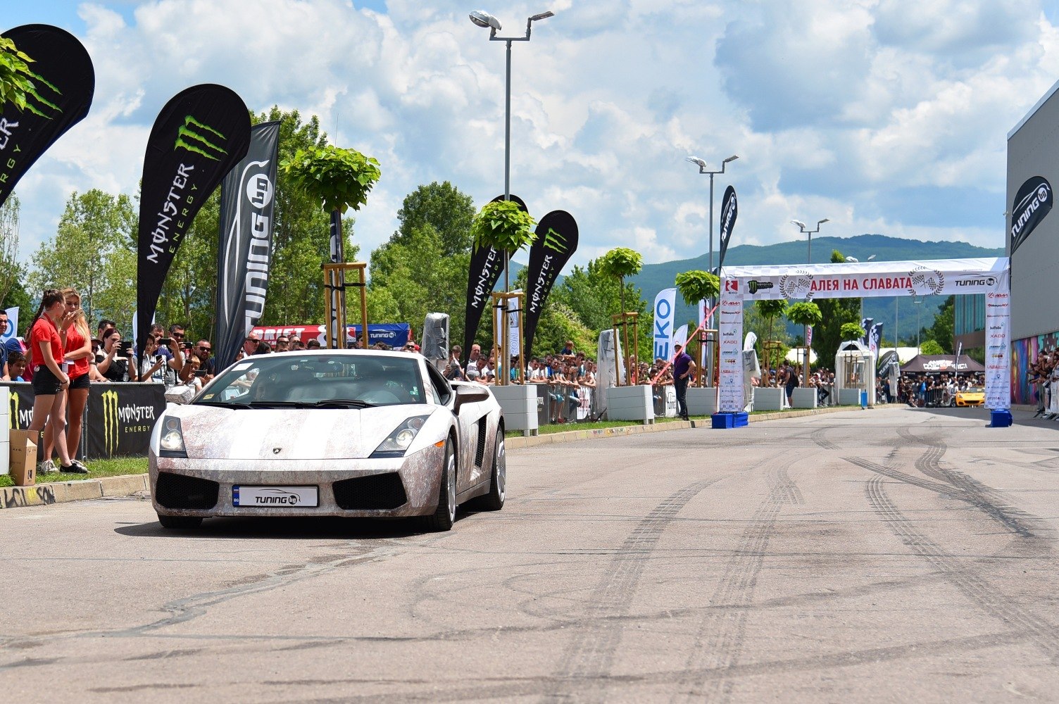 White sports car front view at an outdoor tuning event
