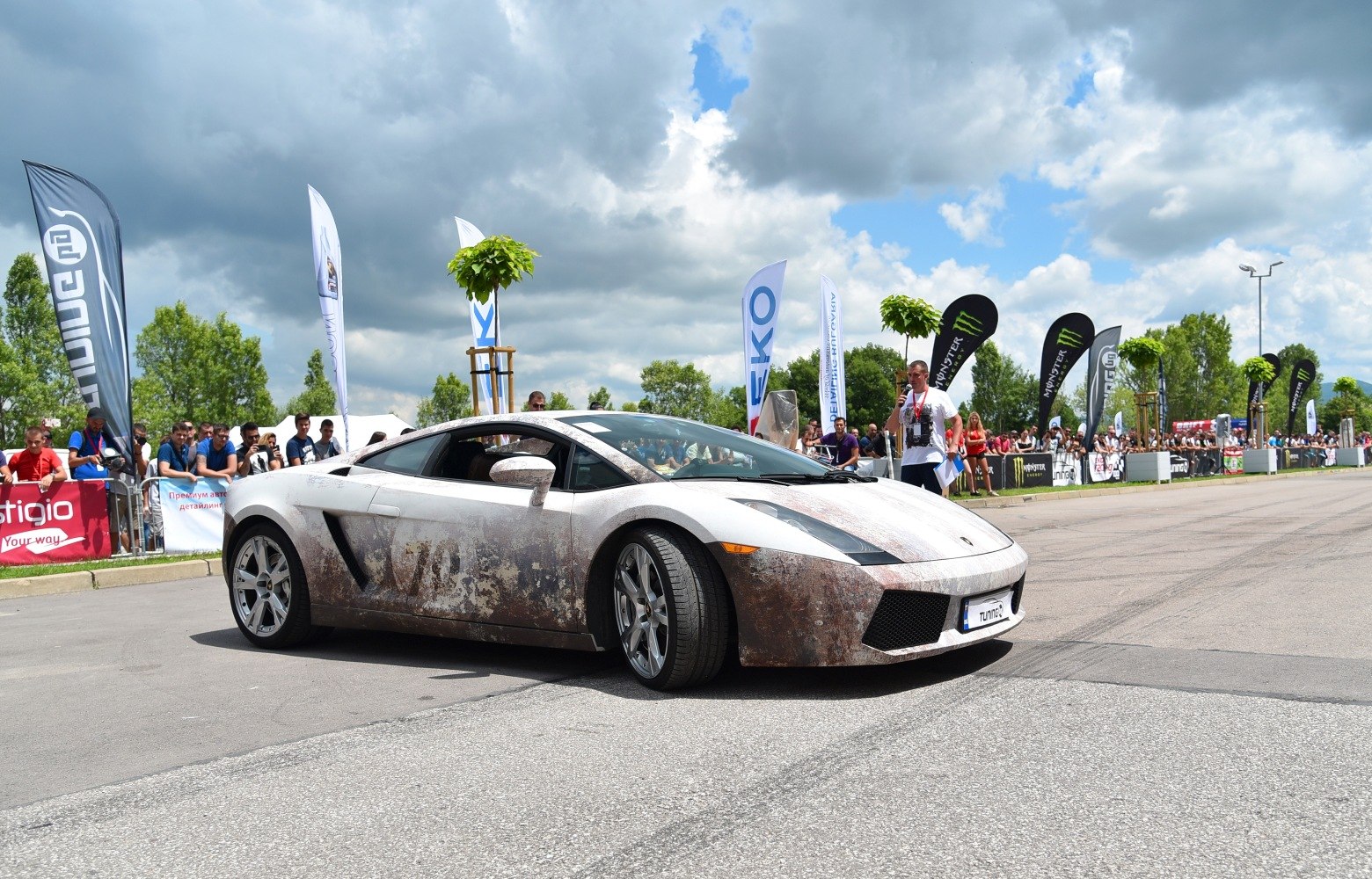 Sports coupe with rust-effect wrap at outdoor event