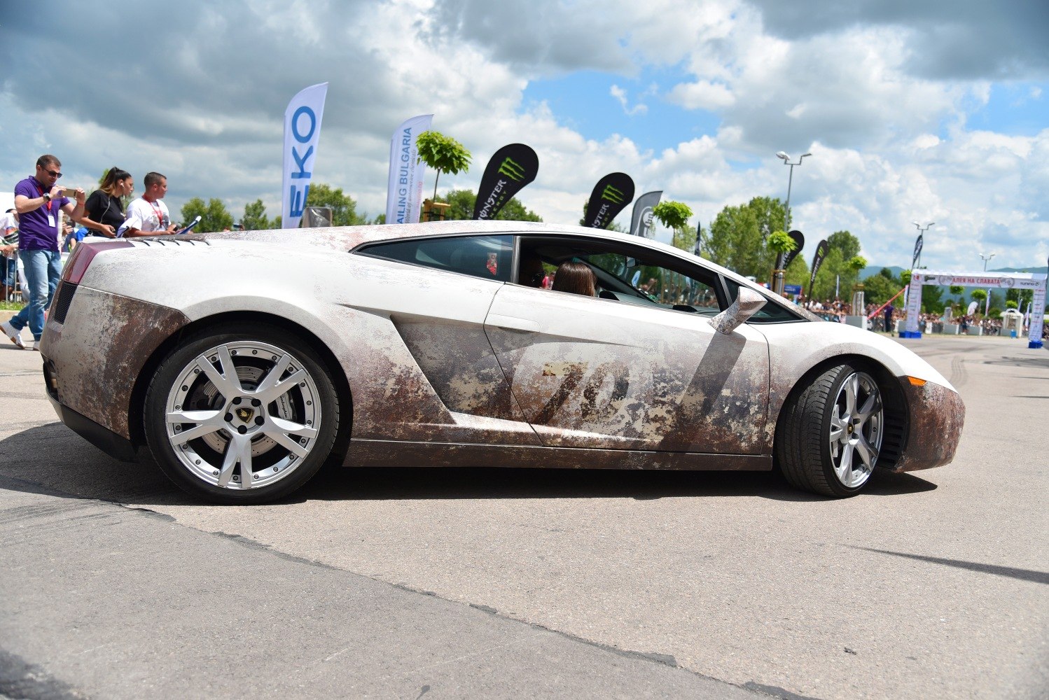 Side profile of a sleek sports coupe with muddy exterior and detailed alloy wheels
