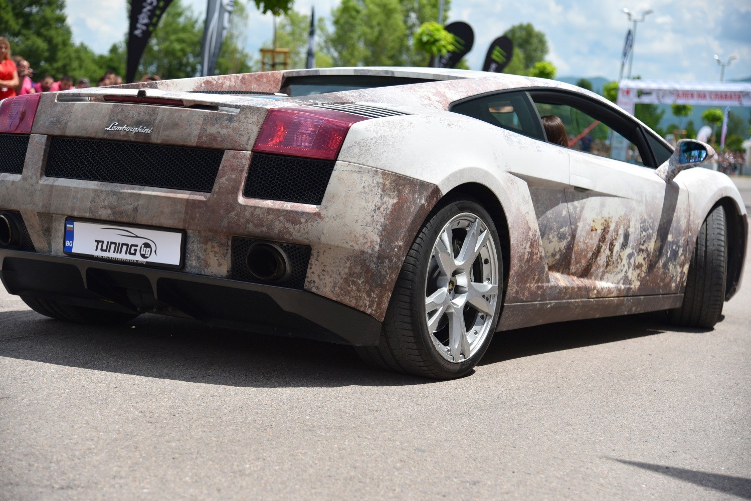 Rear view of sports coupe with rusted patina wrap and alloy wheels