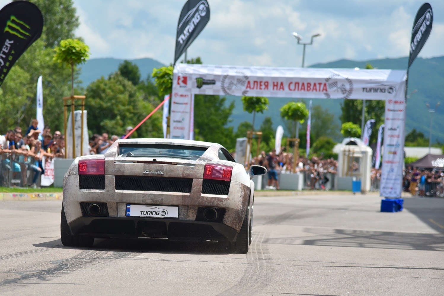Rear view of sports coupe with visible exhaust and tail lights at event