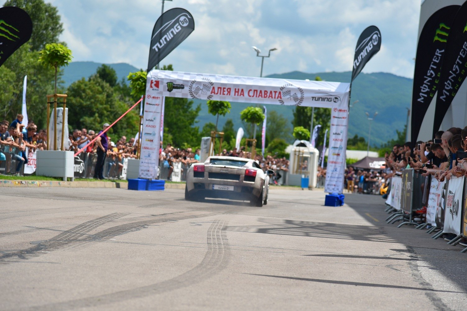 Sports car accelerating at an event with tire marks and crowd