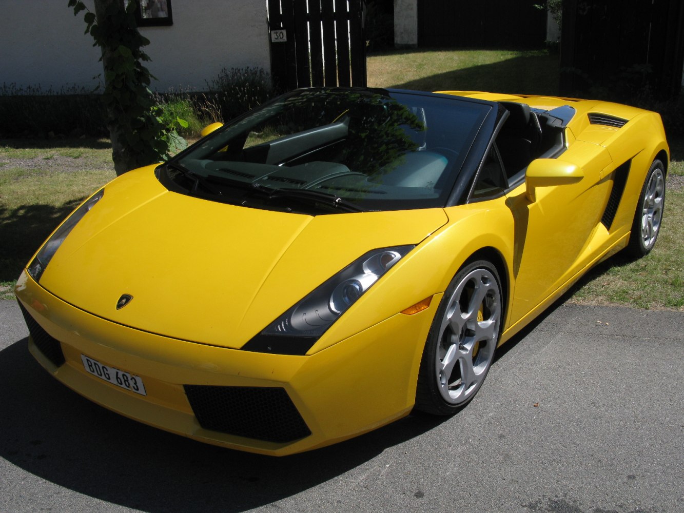 Yellow convertible sports car front view with angular headlights and alloy wheels.