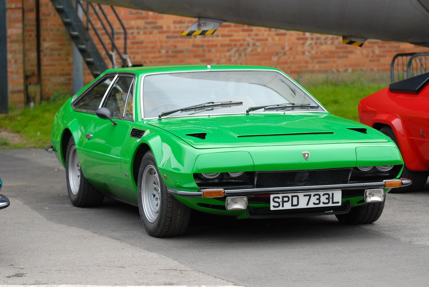 Vintage green sports coupe with dual headlights and sleek hood vents