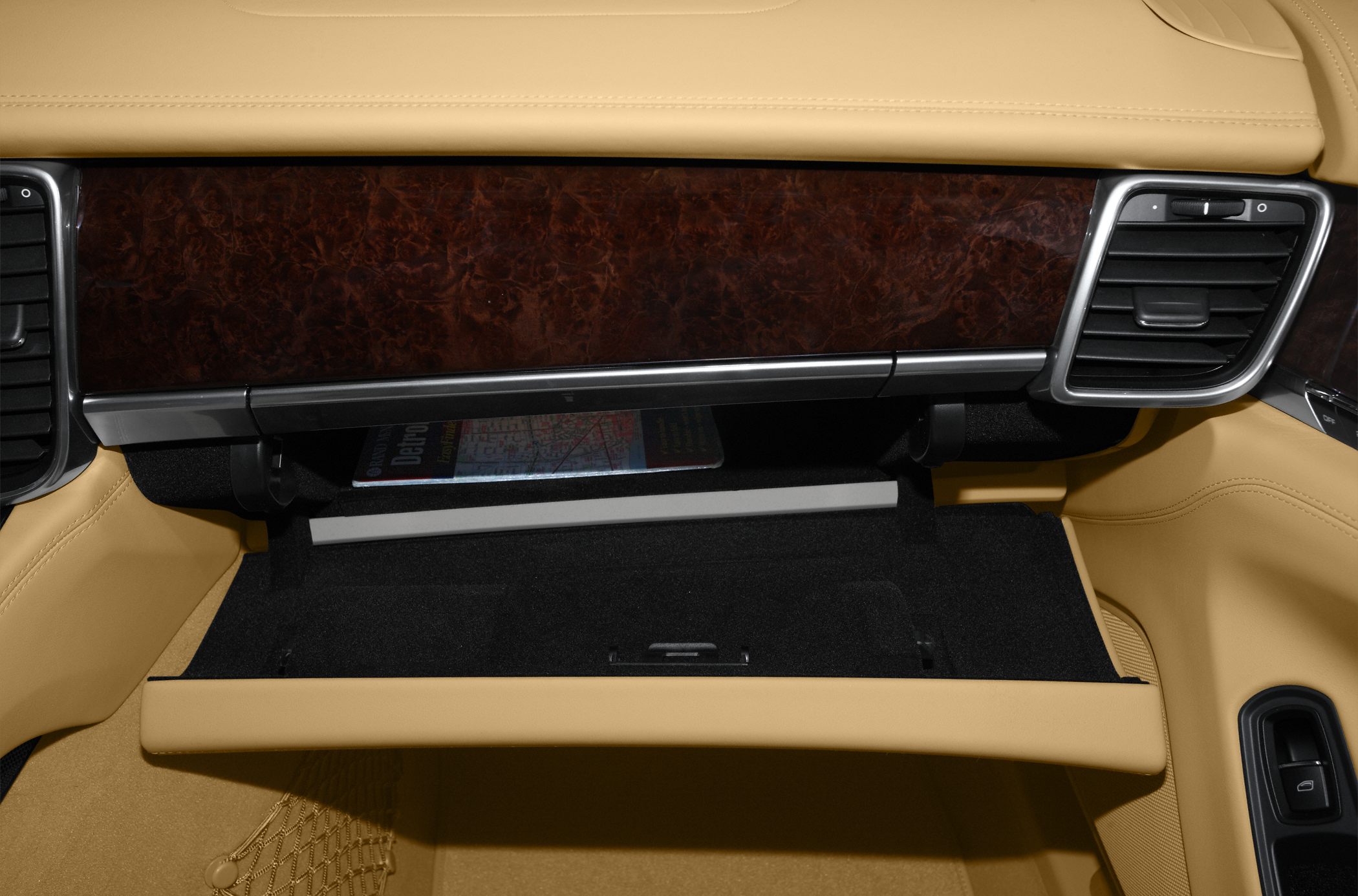 Open glove compartment with wood trim and beige leather interior