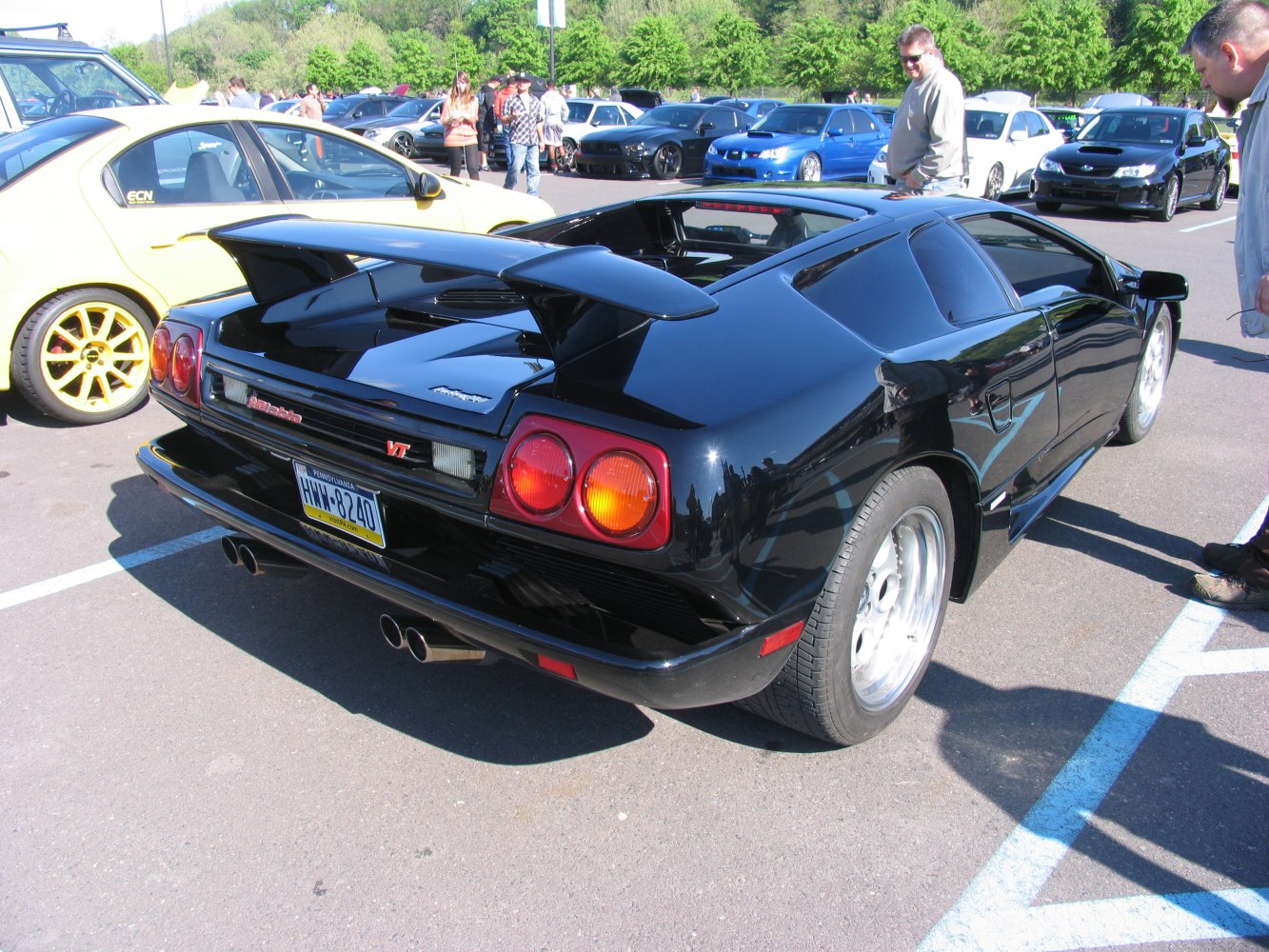 Rear view showing spoiler, round taillights, and quad exhaust of a black sports coupe