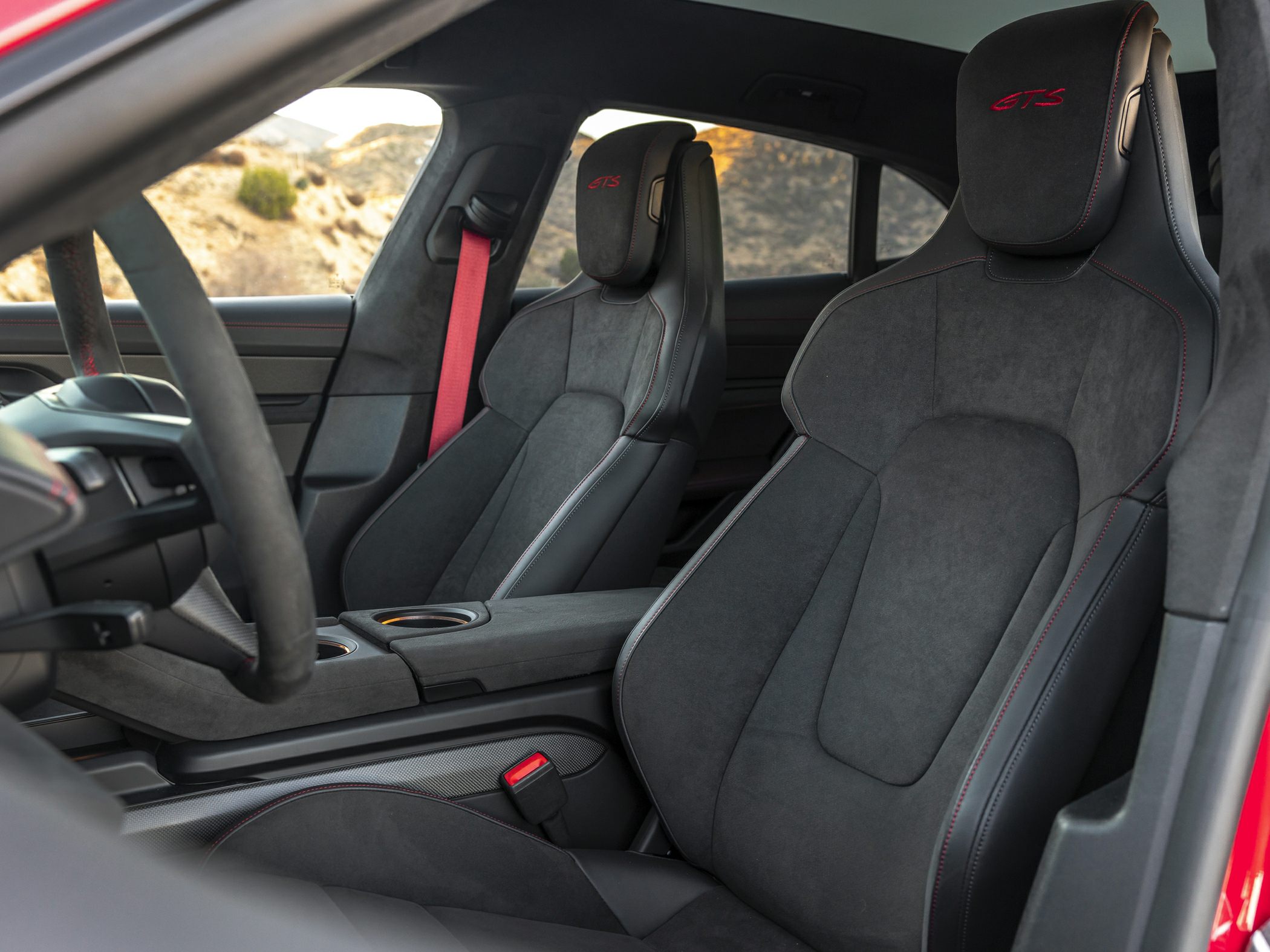 Alcantara GTS seats with red stitching and matching red seatbelts inside a luxury electric vehicle.