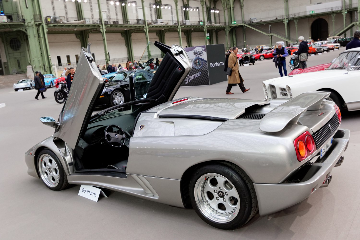 Silver sports car with open scissor doors and rear wing spoiler