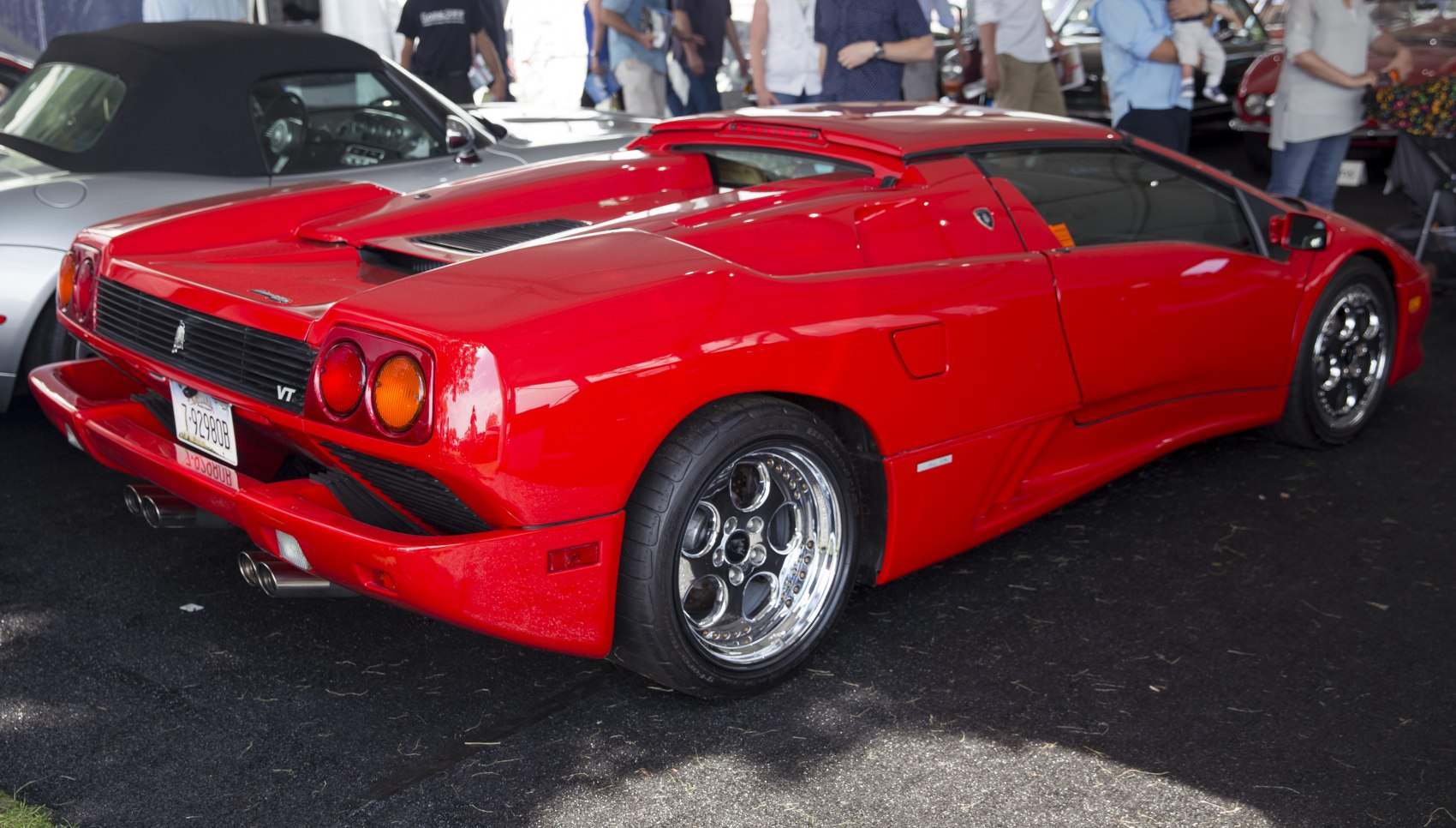 Red convertible sports car rear with chrome multi-spoke wheels