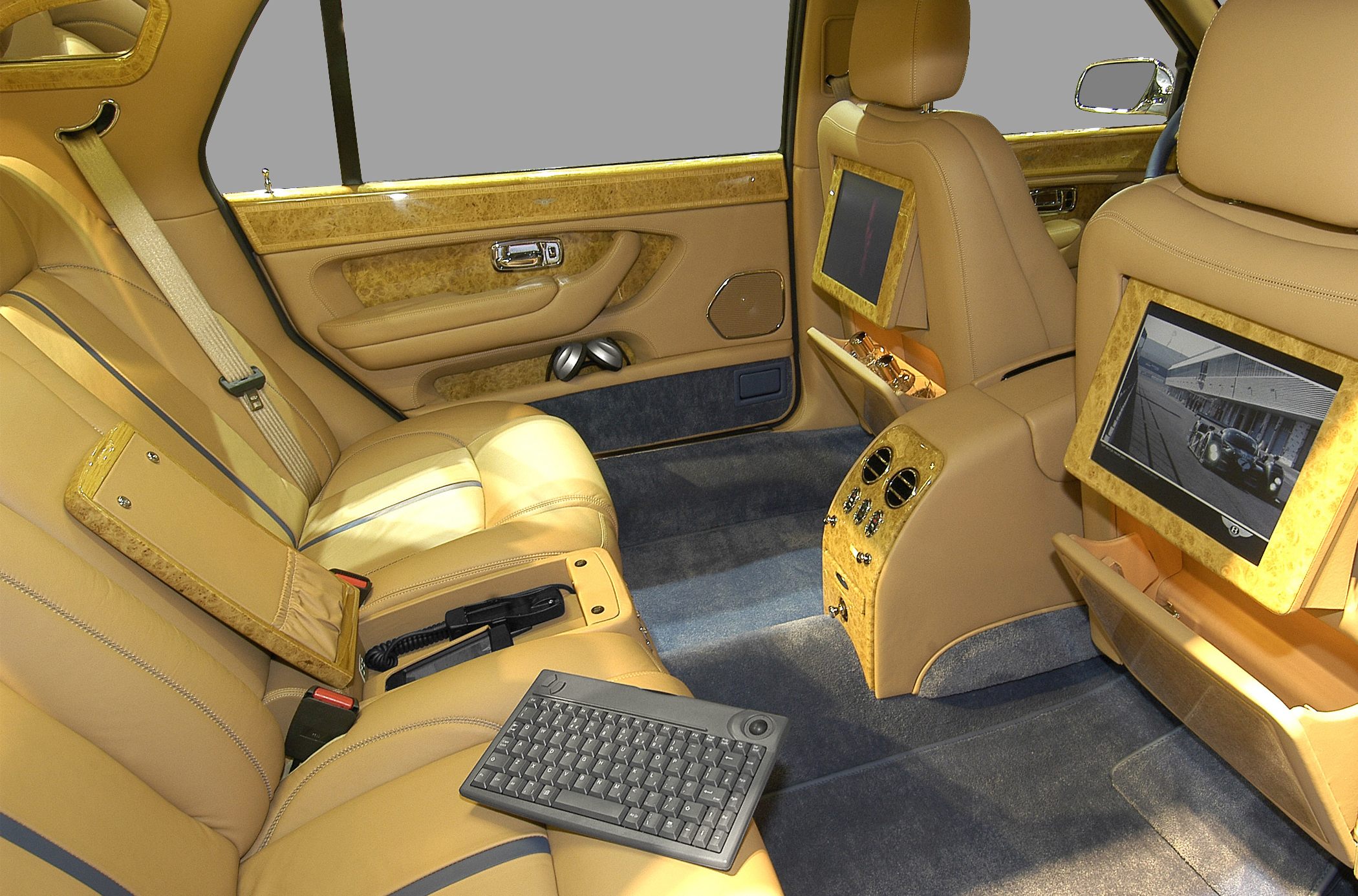 Luxury beige leather rear seating with dual entertainment screens and premium wood accents