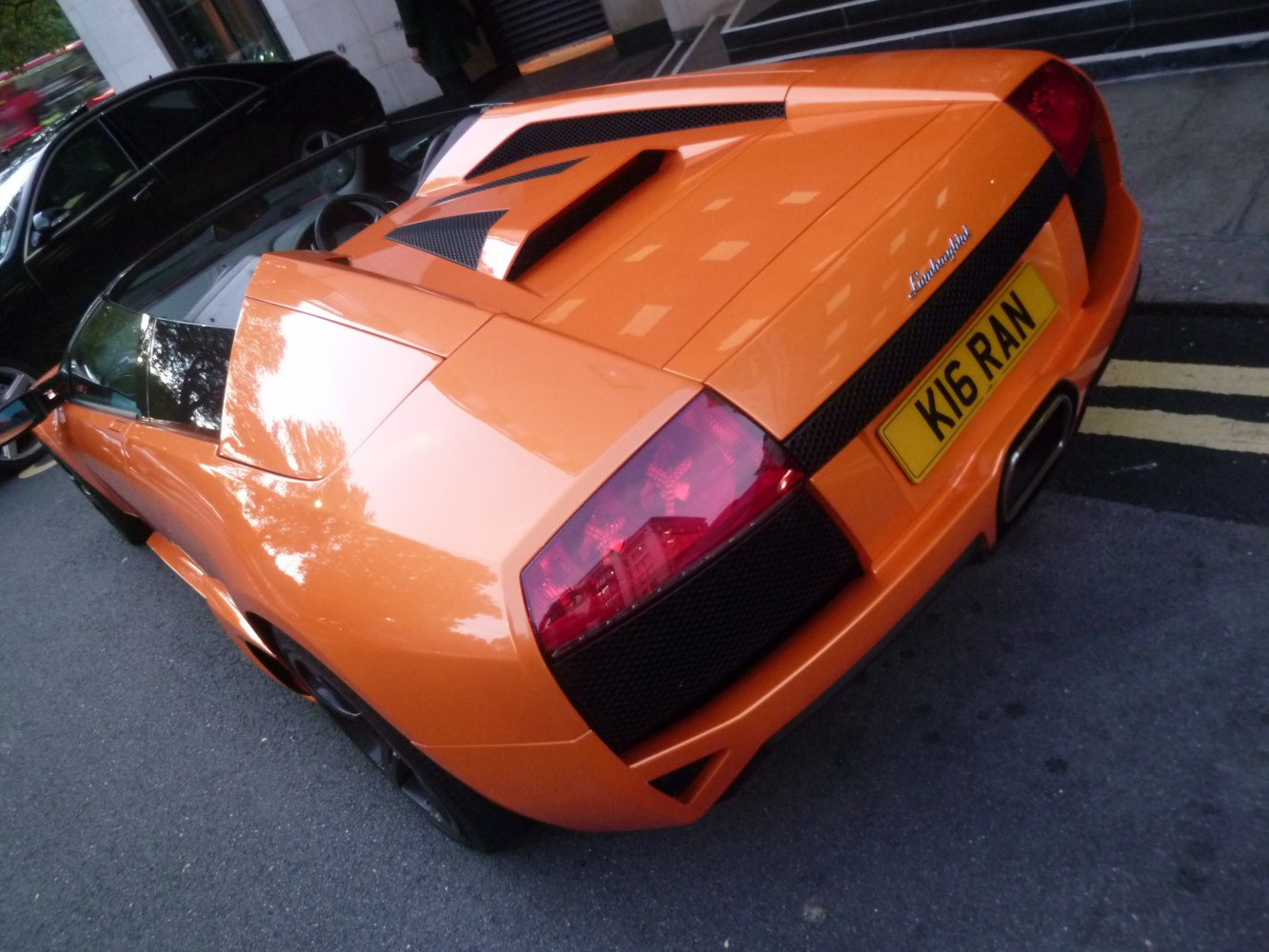 Rear view of orange supercar with distinctive tail lights and engine cover