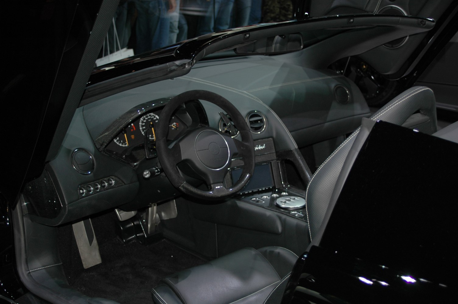 Luxury sports car dashboard and steering wheel with carbon fiber accents.