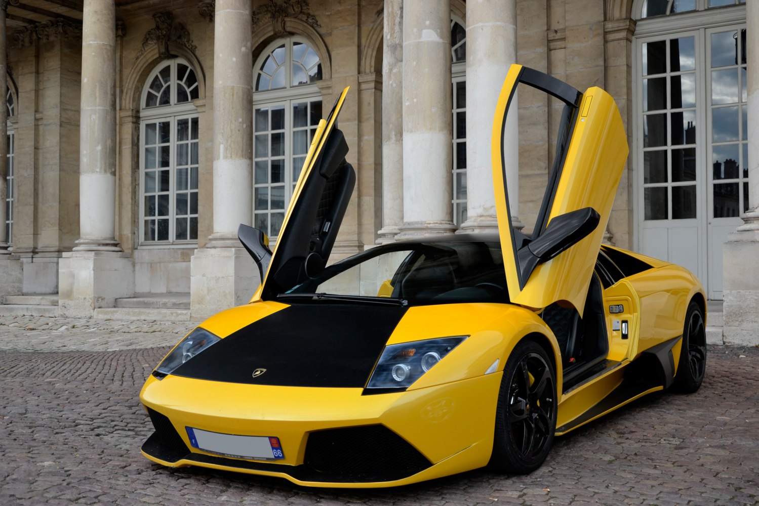 Yellow supercar with upward-opening scissor doors and black front hood