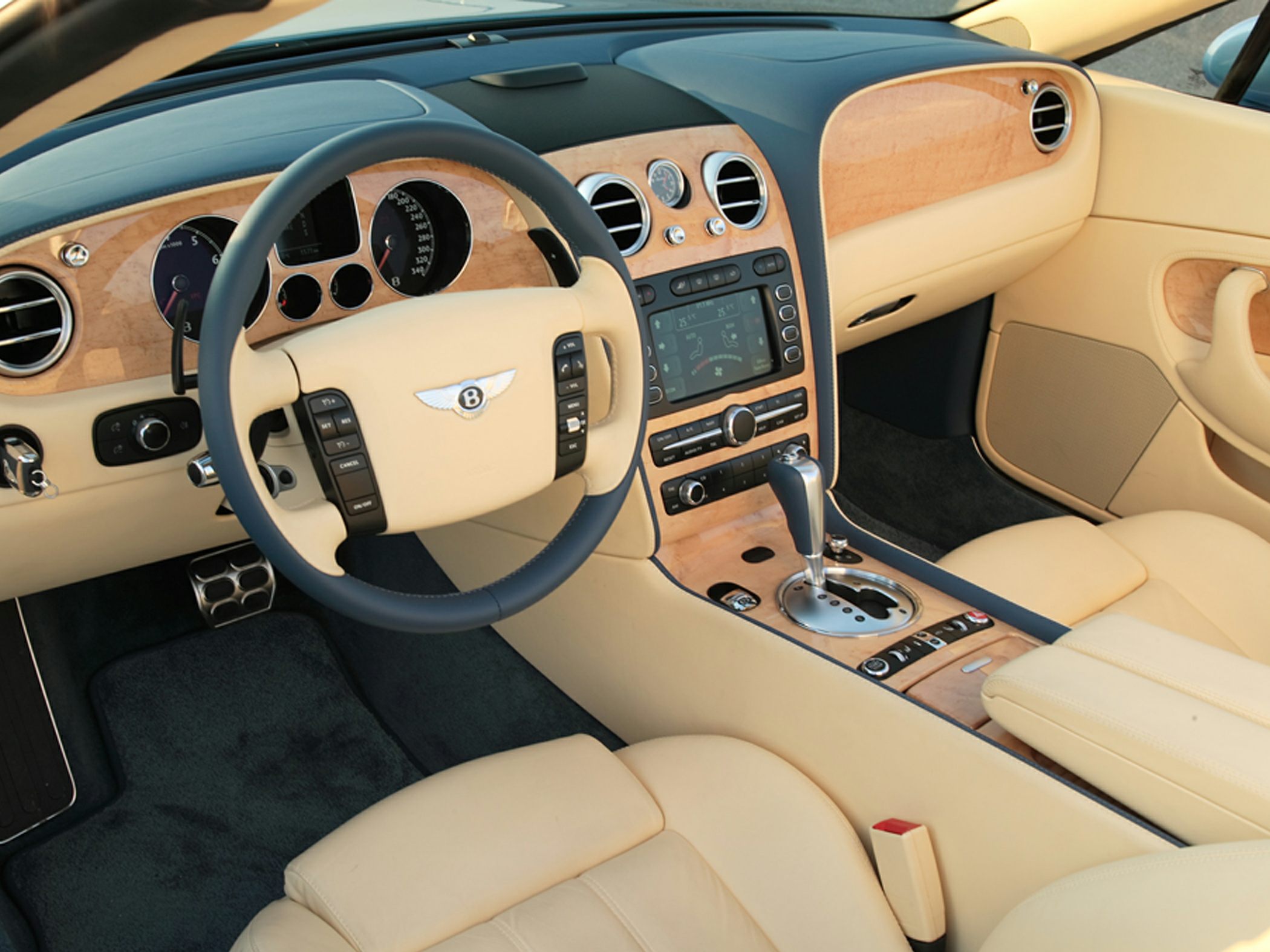 Beige leather interior with wood trim, digital control console, and automatic gear shifter