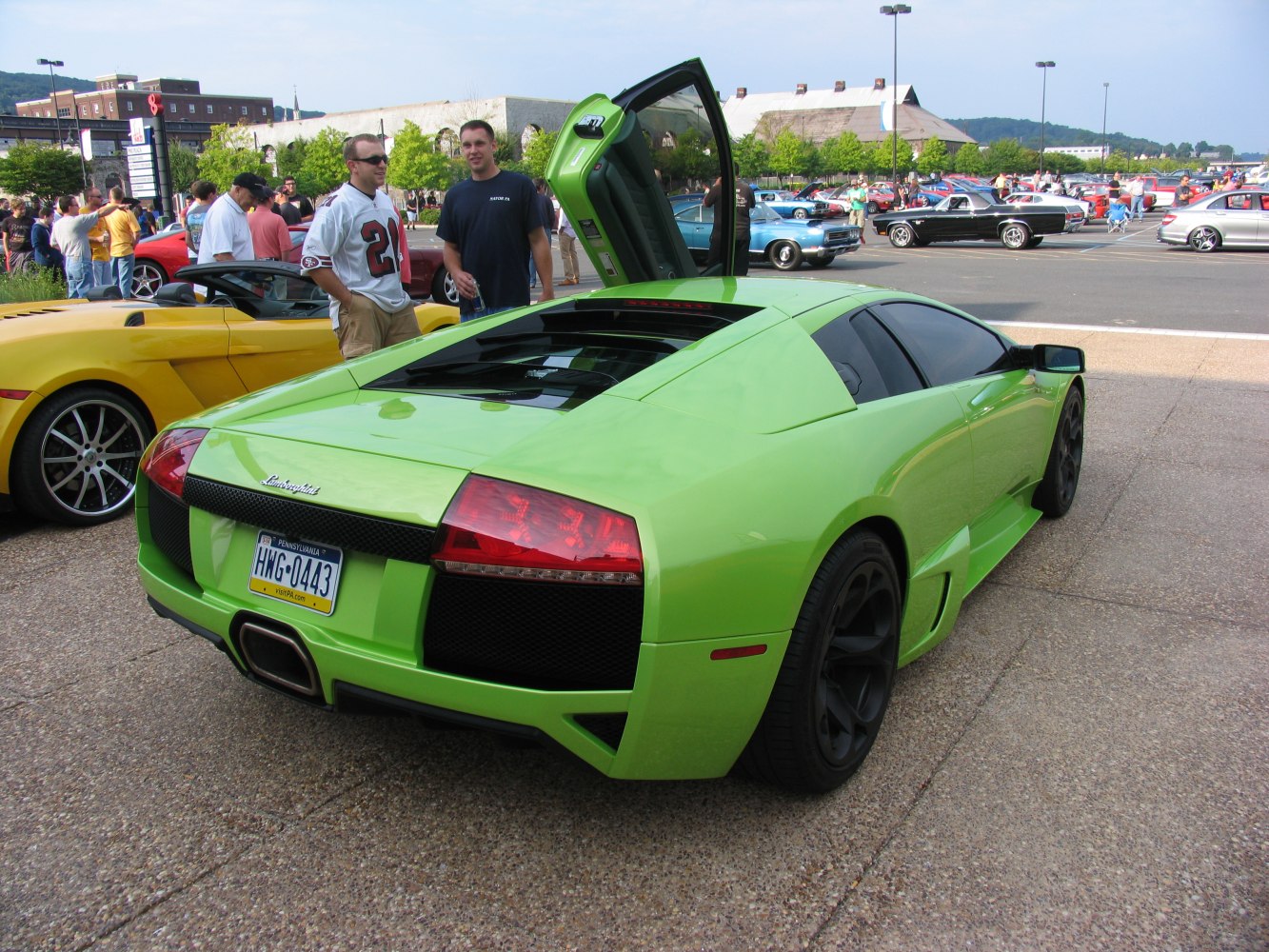 Rear view of green sports car with open vertical scissor door