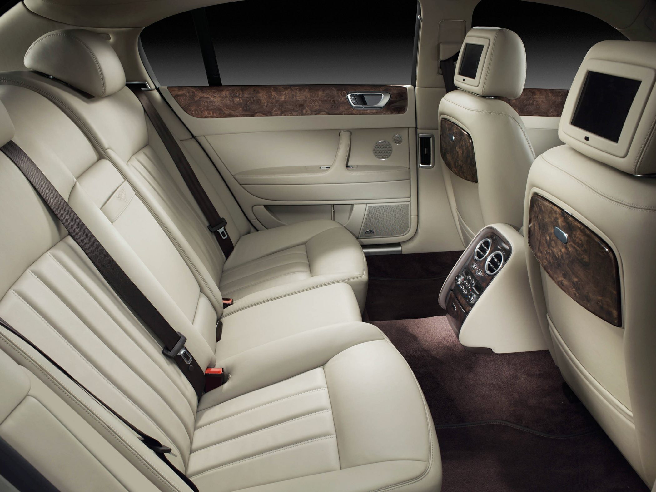 Rear seat interior with beige leather, wood trim, and entertainment screens