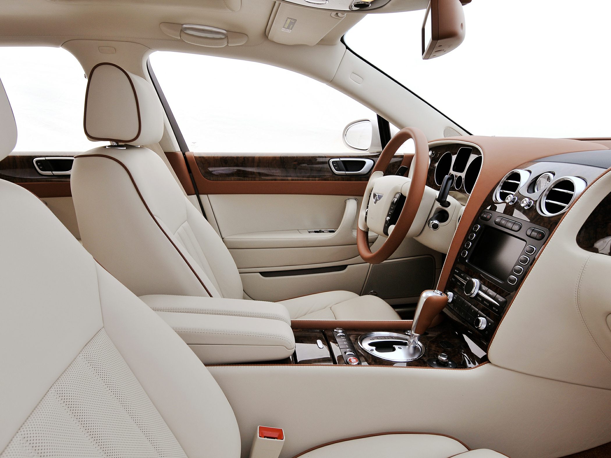 Beige leather seats and wood trim interior with automatic gear shift and premium steering wheel.