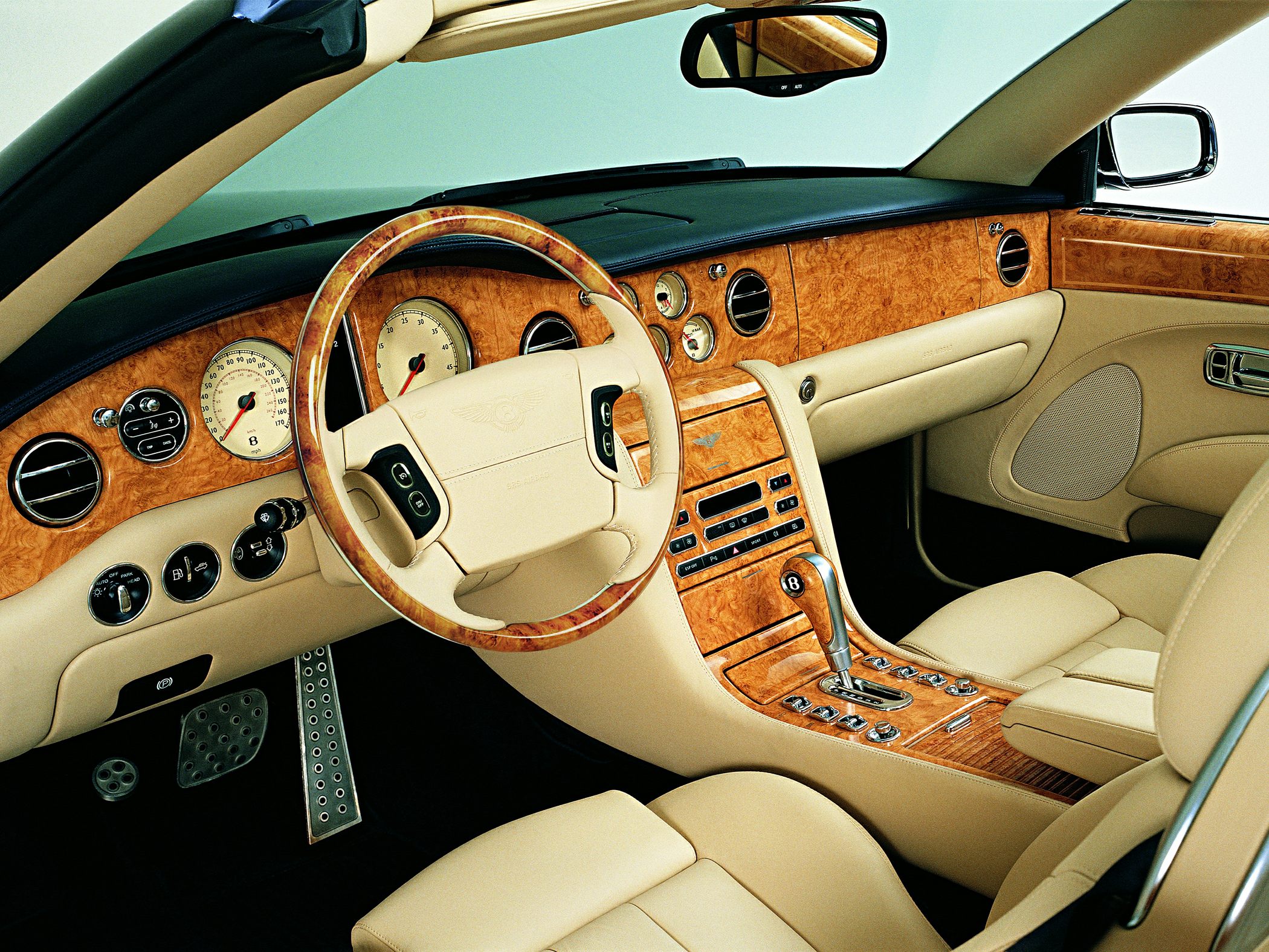 Wooden dashboard and beige leather interior with steering wheel and gear shift