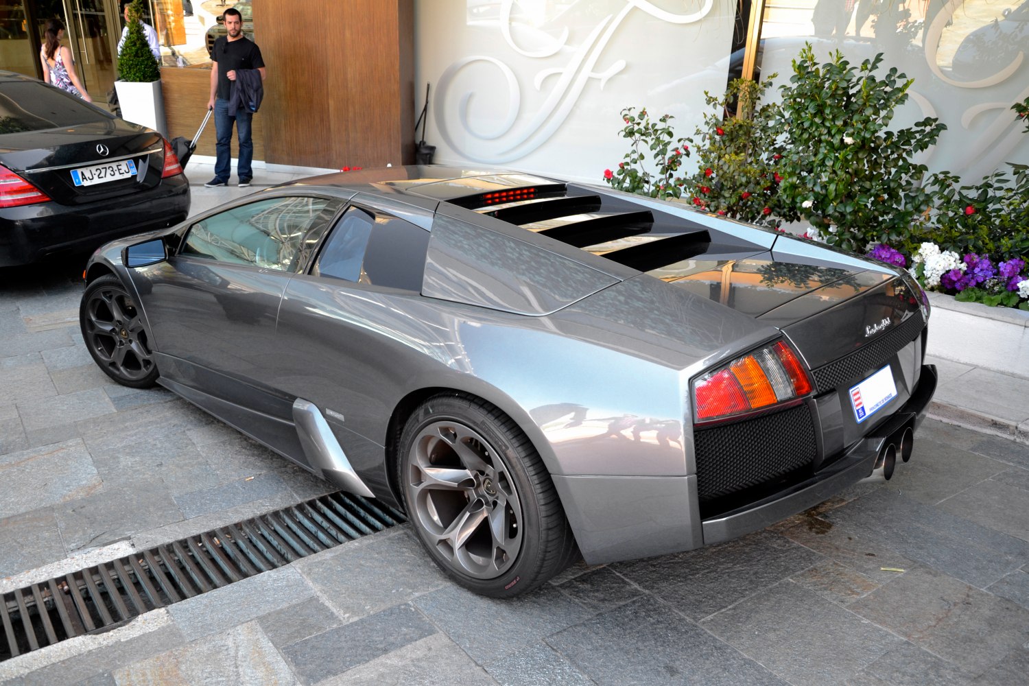 High-angle rear and side view of a metallic gray supercar with rear engine vents.