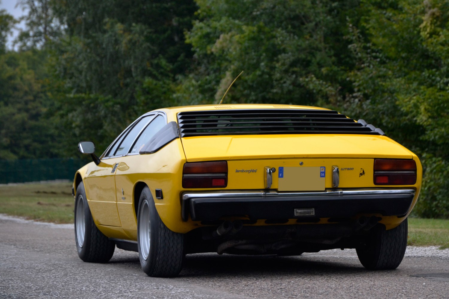 Yellow classic sports coupe rear with tail lights and window louvers