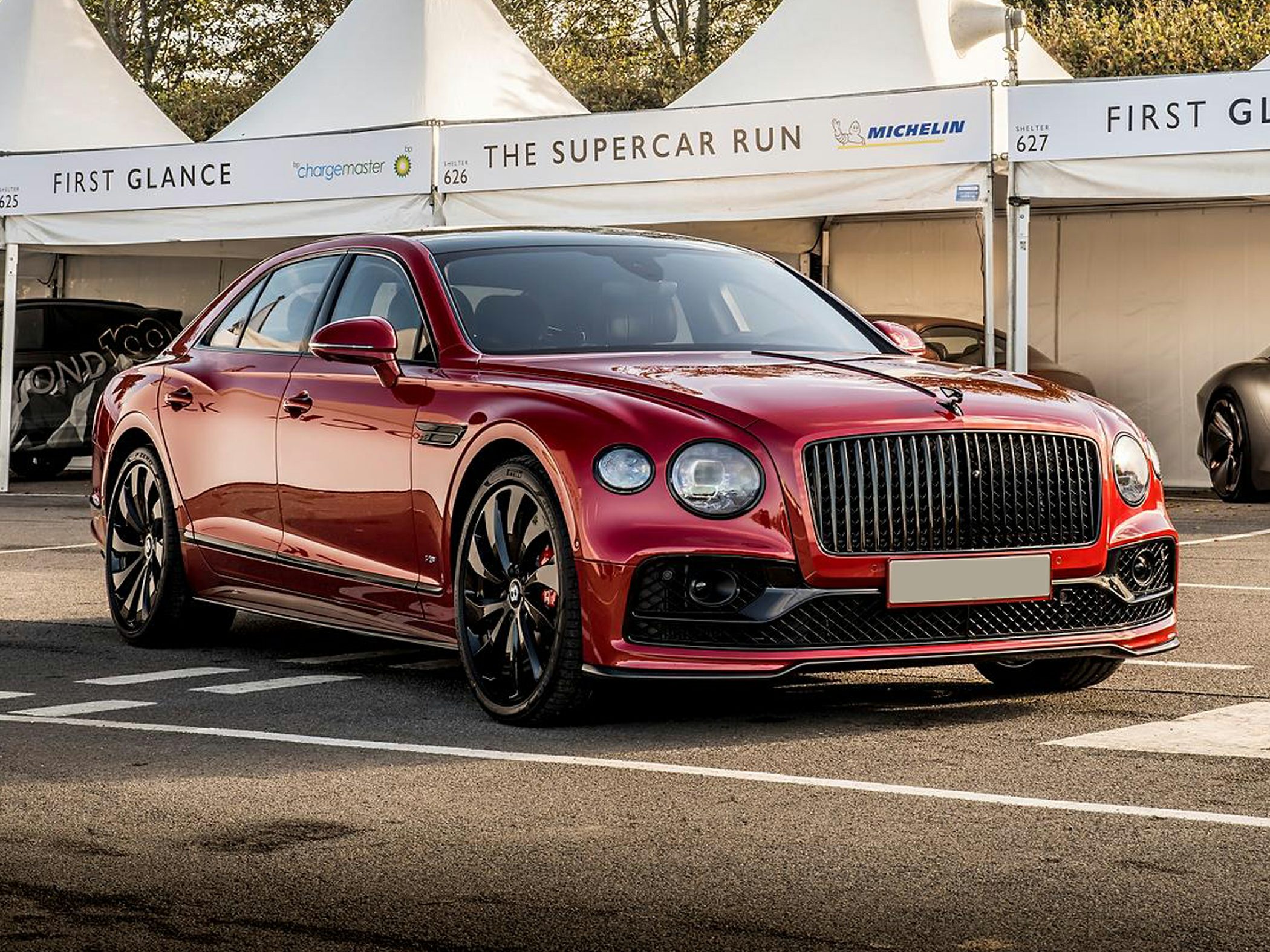 Luxury sedan with black grille and wheels, sleek red exterior.