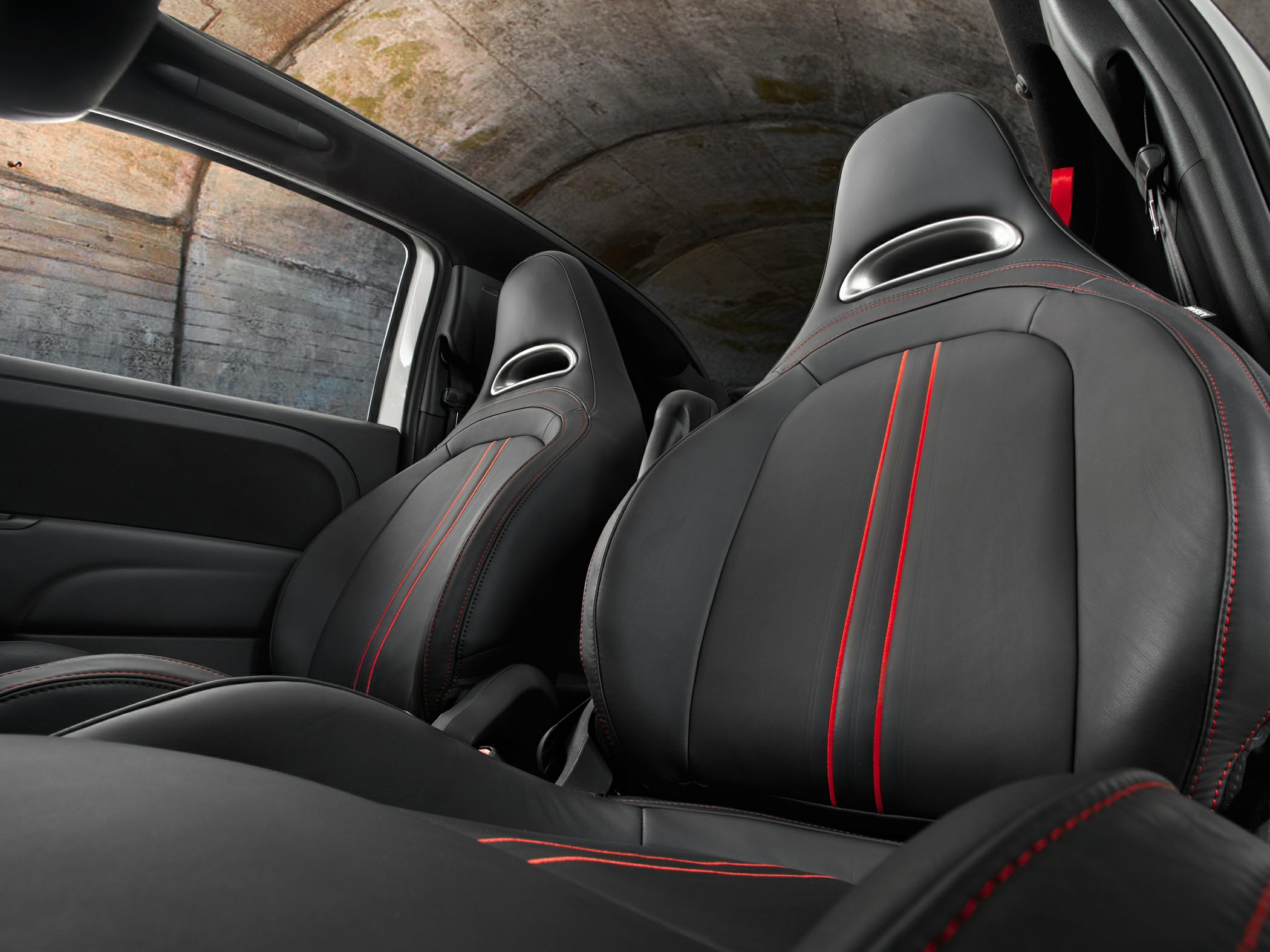 Black leather sports seats with red stitching in car interior