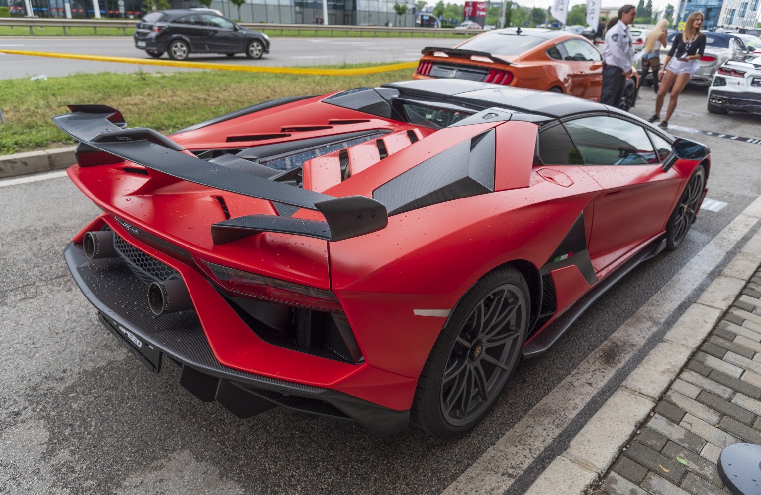 Red sports car rear with large carbon fiber spoiler and aggressive aerodynamics
