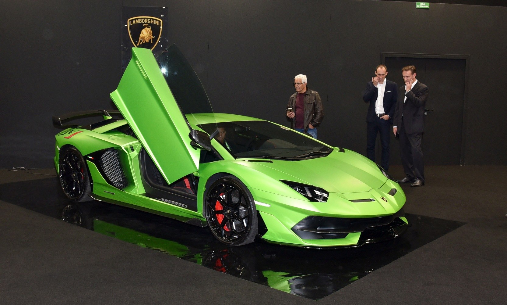 Green supercar with open scissor door and large rear wing