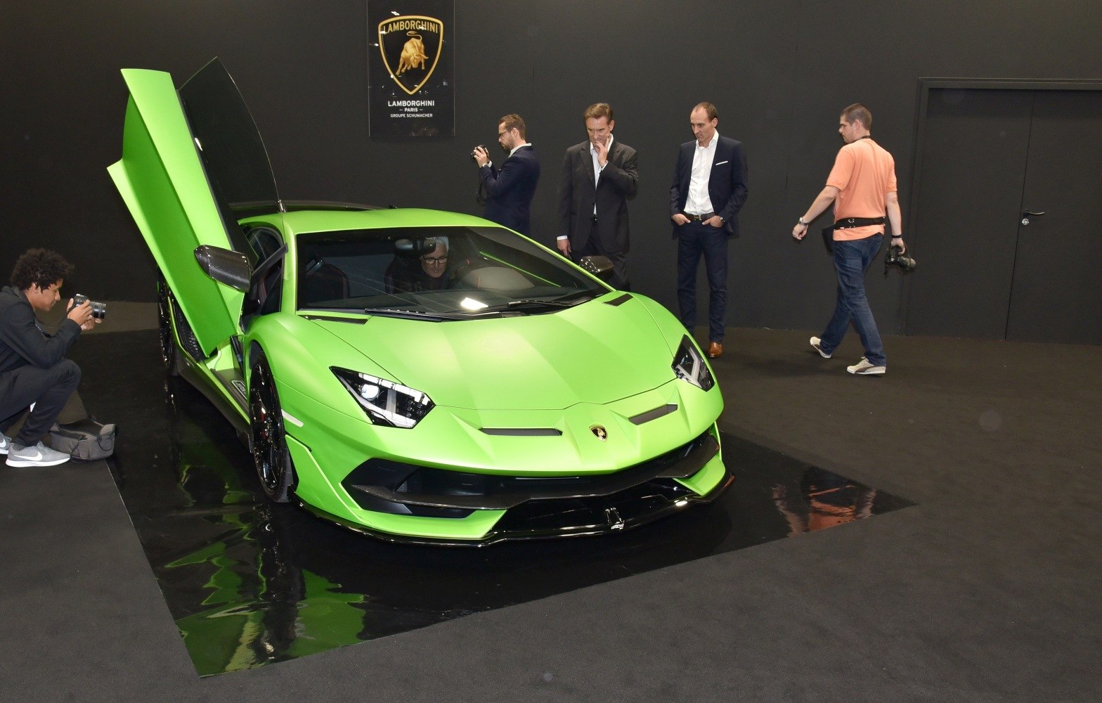 Green supercar with open scissor door and aggressive front design