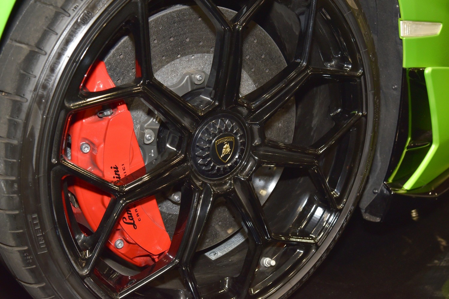 Black alloy wheel with red brake caliper and perforated disc