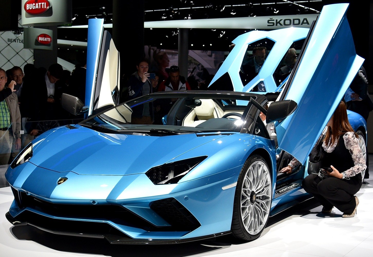 Blue sports car with open scissor doors and multi-spoke wheels