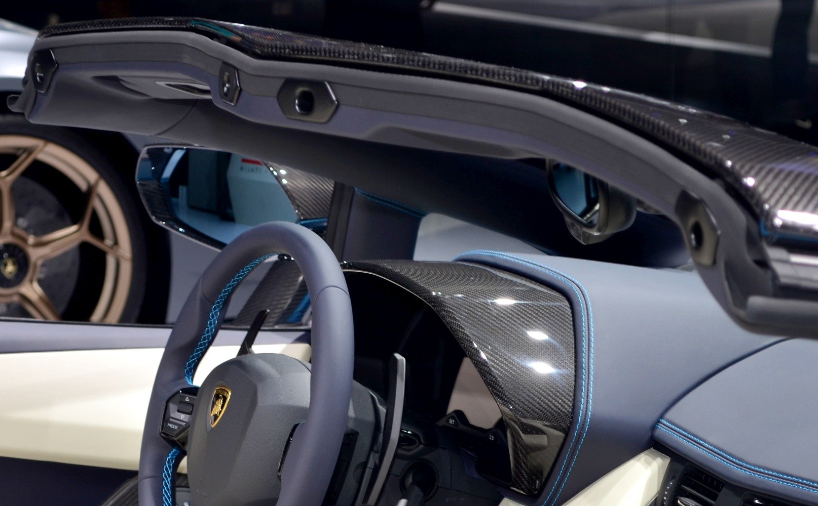 Luxury roadster interior with carbon fiber dashboard and blue stitching