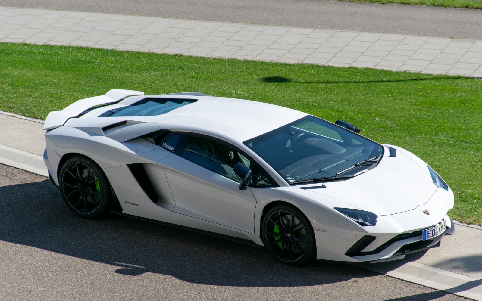 Sleek side profile and transparent rear engine cover of a white sports car.
