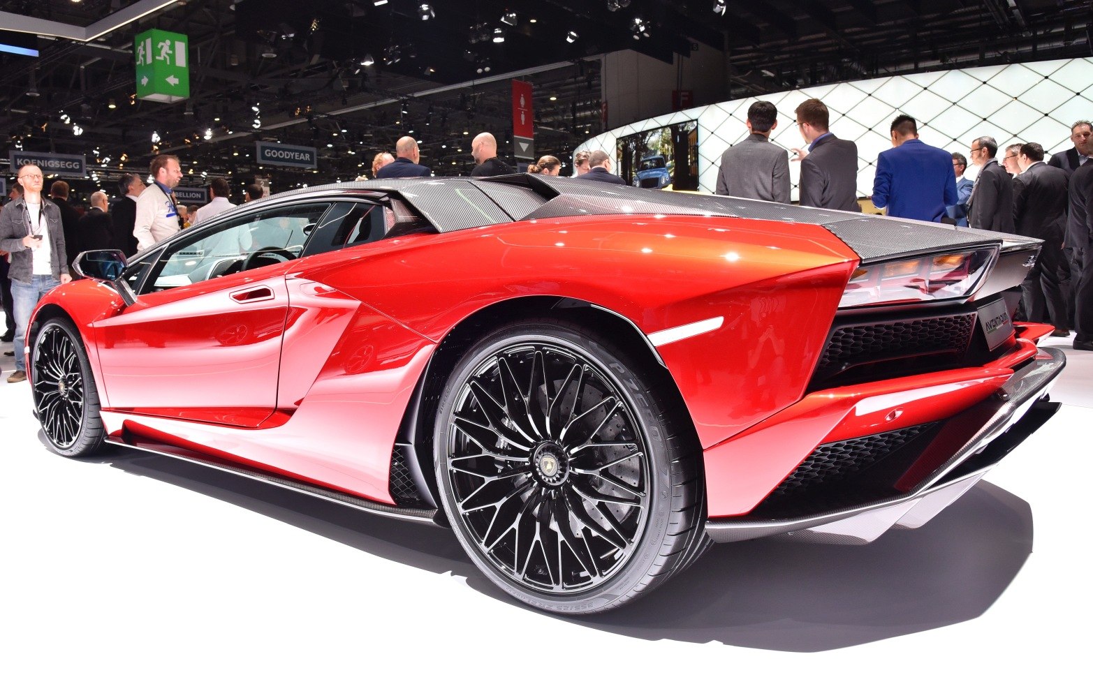 Red sports car rear side with black multi-spoke wheels and carbon fiber accents