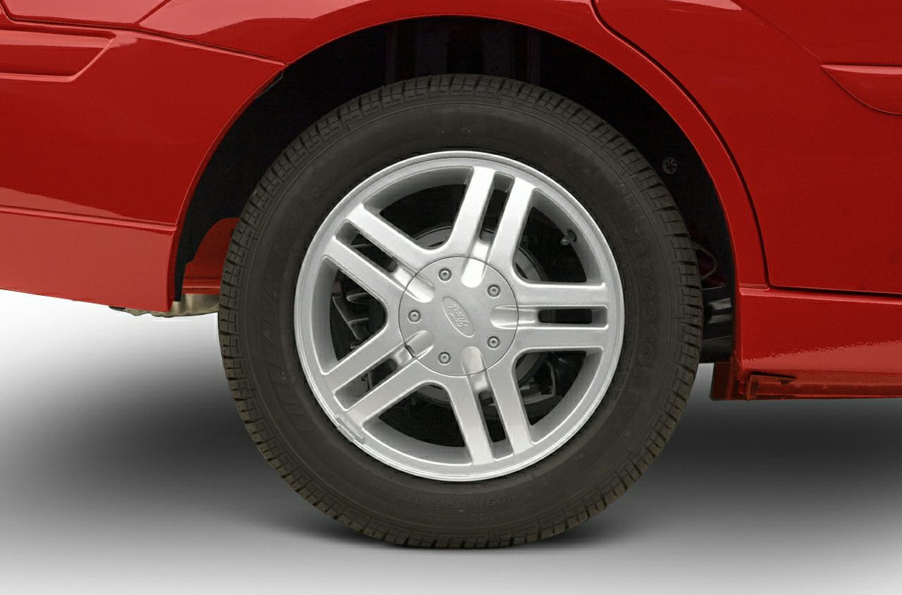 Close-up of silver alloy wheel and tire on red car rear section