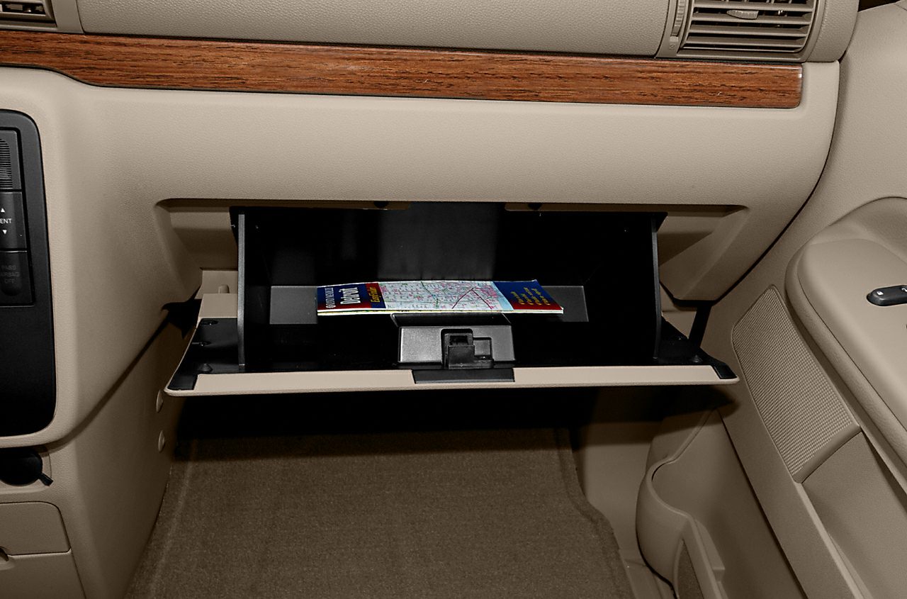 Open glove compartment with map inside beige interior and wood trim dashboard