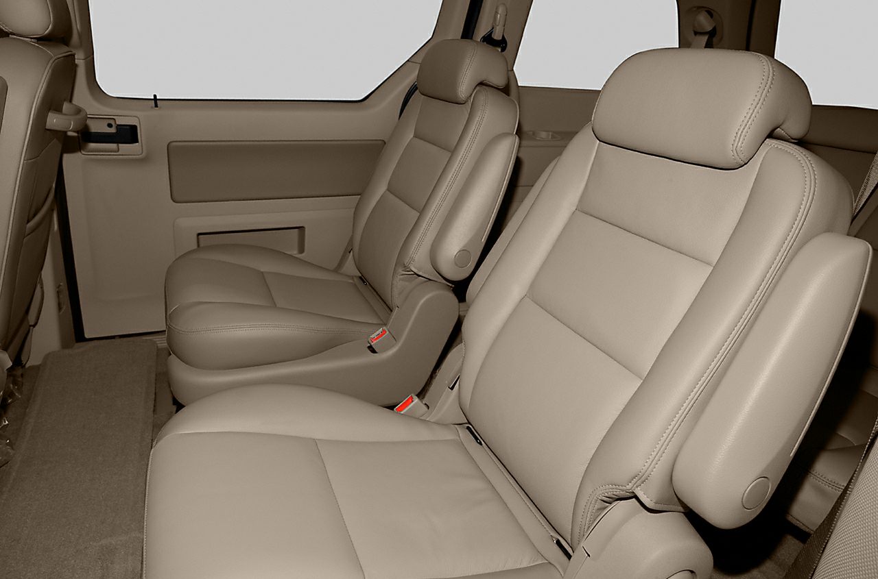 Beige leather captain seats with armrests inside a vehicle.