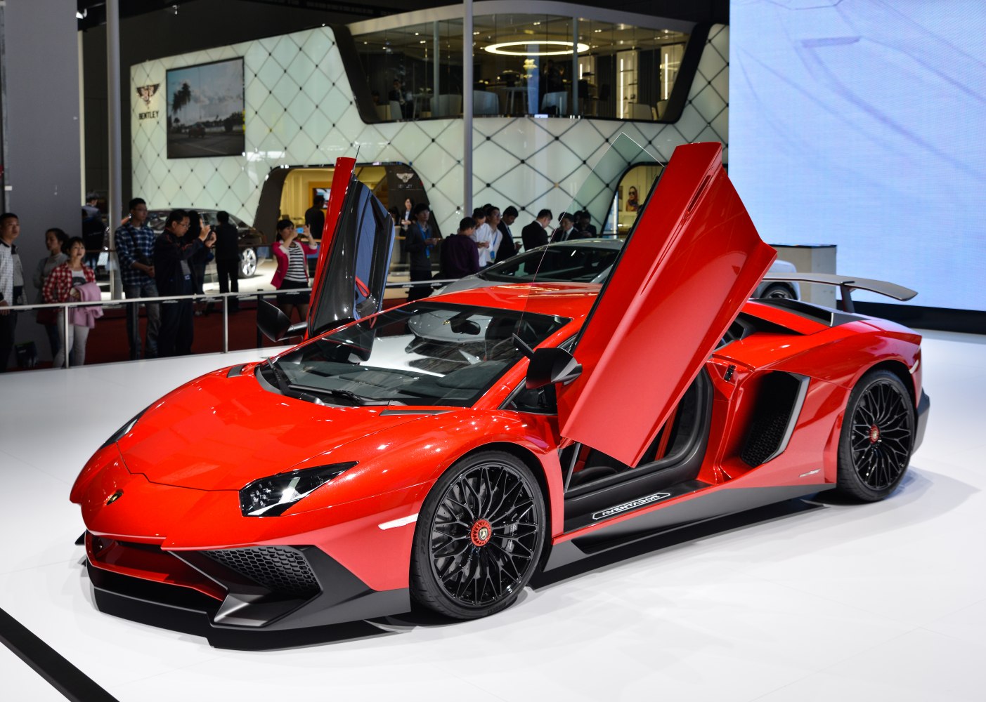 Red sports car with scissor doors and black multi-spoke wheels