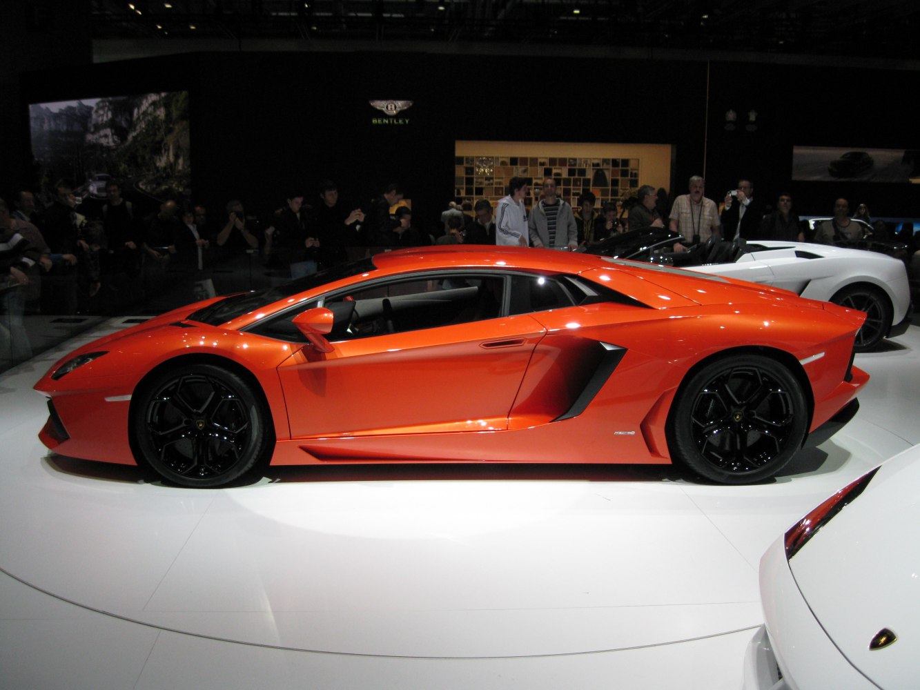 Sleek side profile of a bright orange sports coupe with aerodynamic design and black wheels