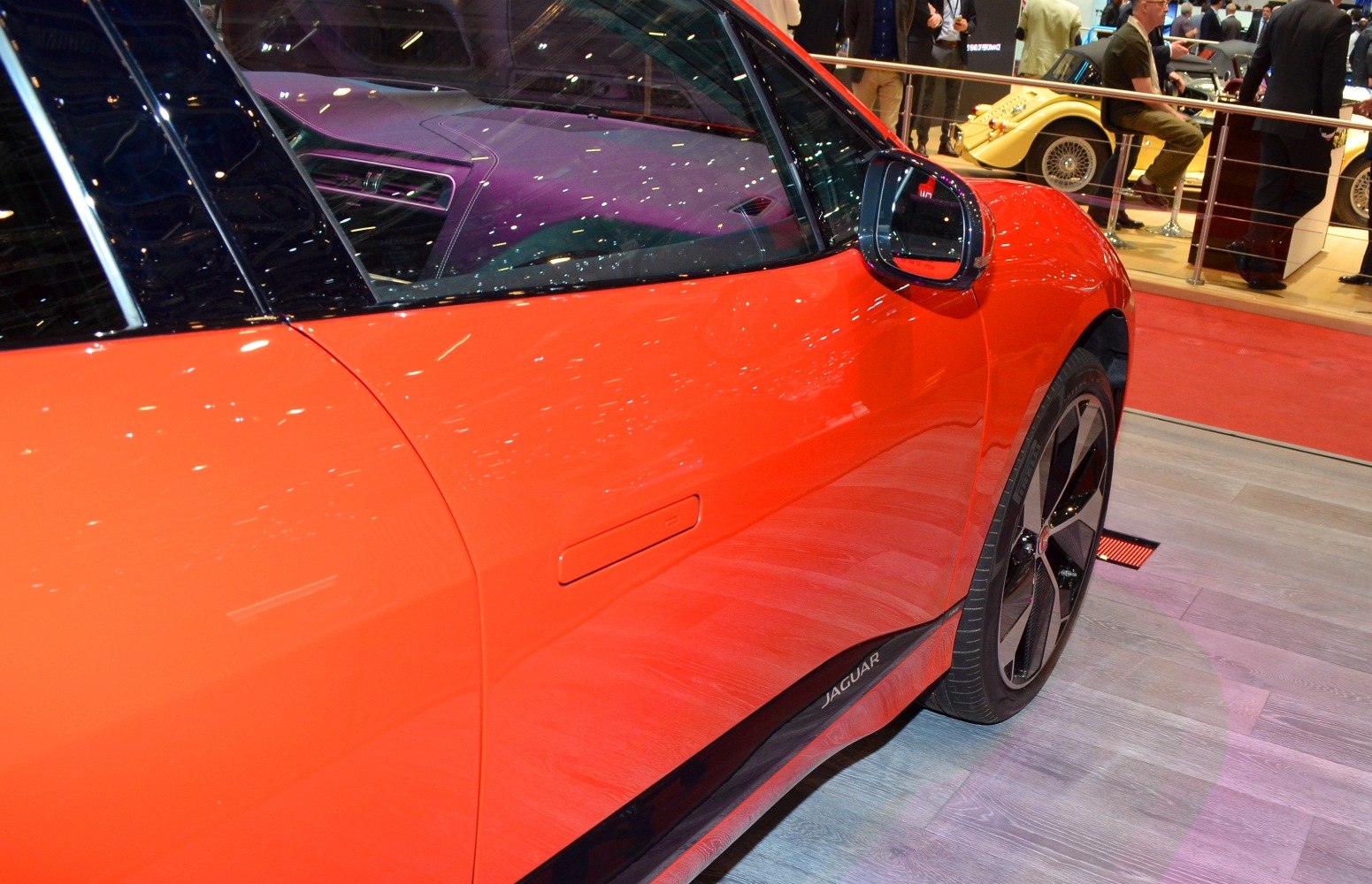 Close-up of side door, mirror, and wheel on orange electric SUV