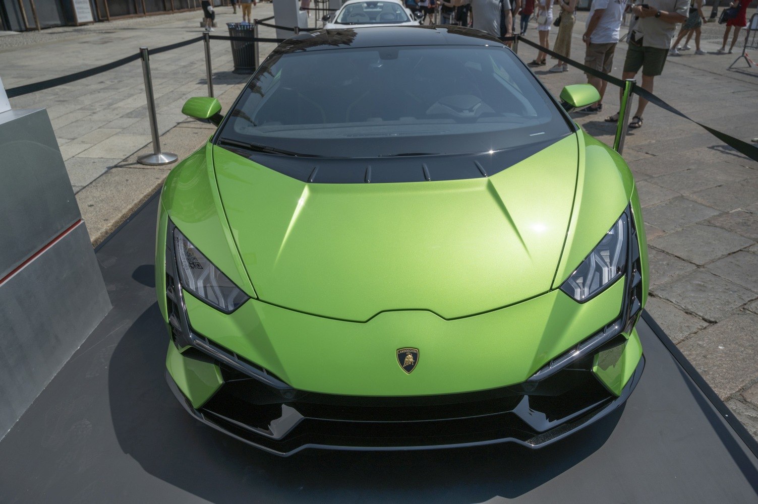 Green supercar front with sharp headlights and aerodynamic hood.