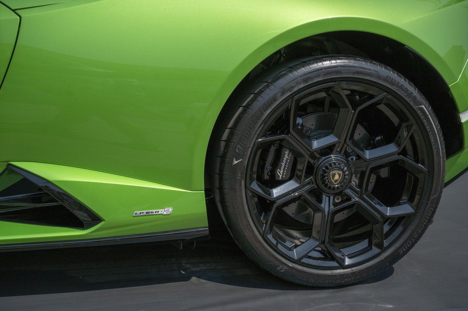Black geometric alloy wheel with green aerodynamic side panel and badge
