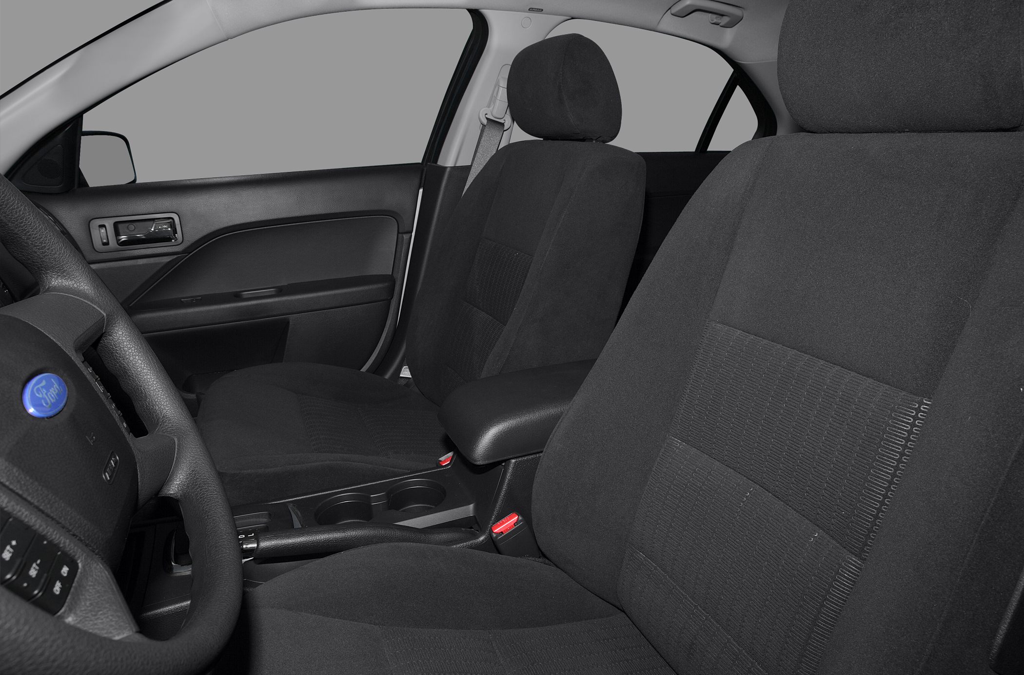 Close-up of front seats, steering wheel, and center console with cup holders.