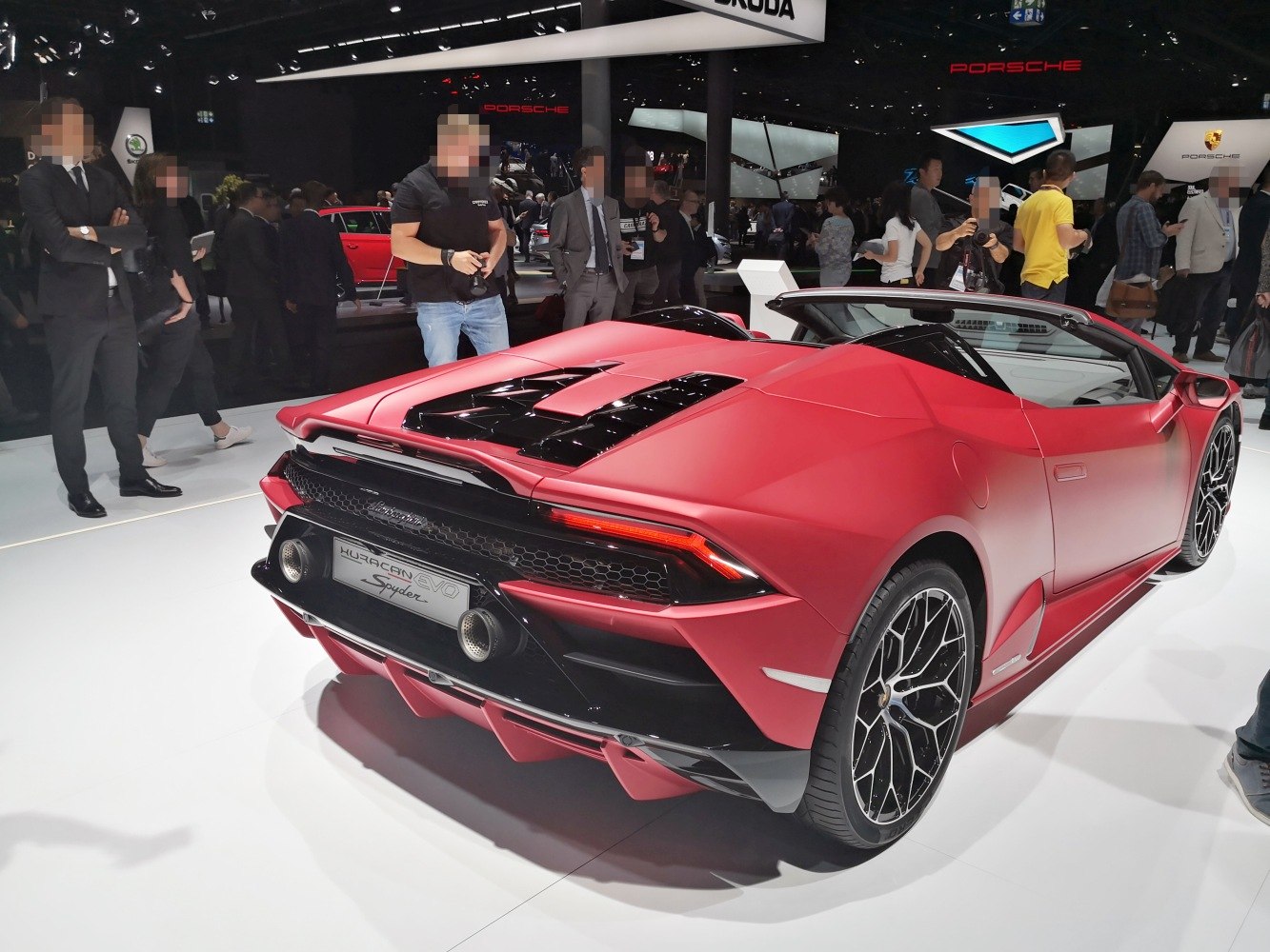 Rear and side view of a convertible sports car with matte red finish and distinctive exhaust.