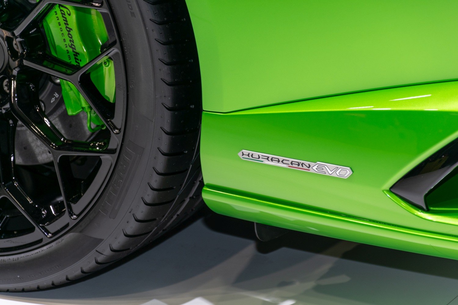 Close-up of black alloy wheel, green brake caliper, and EVO side badge on green paint