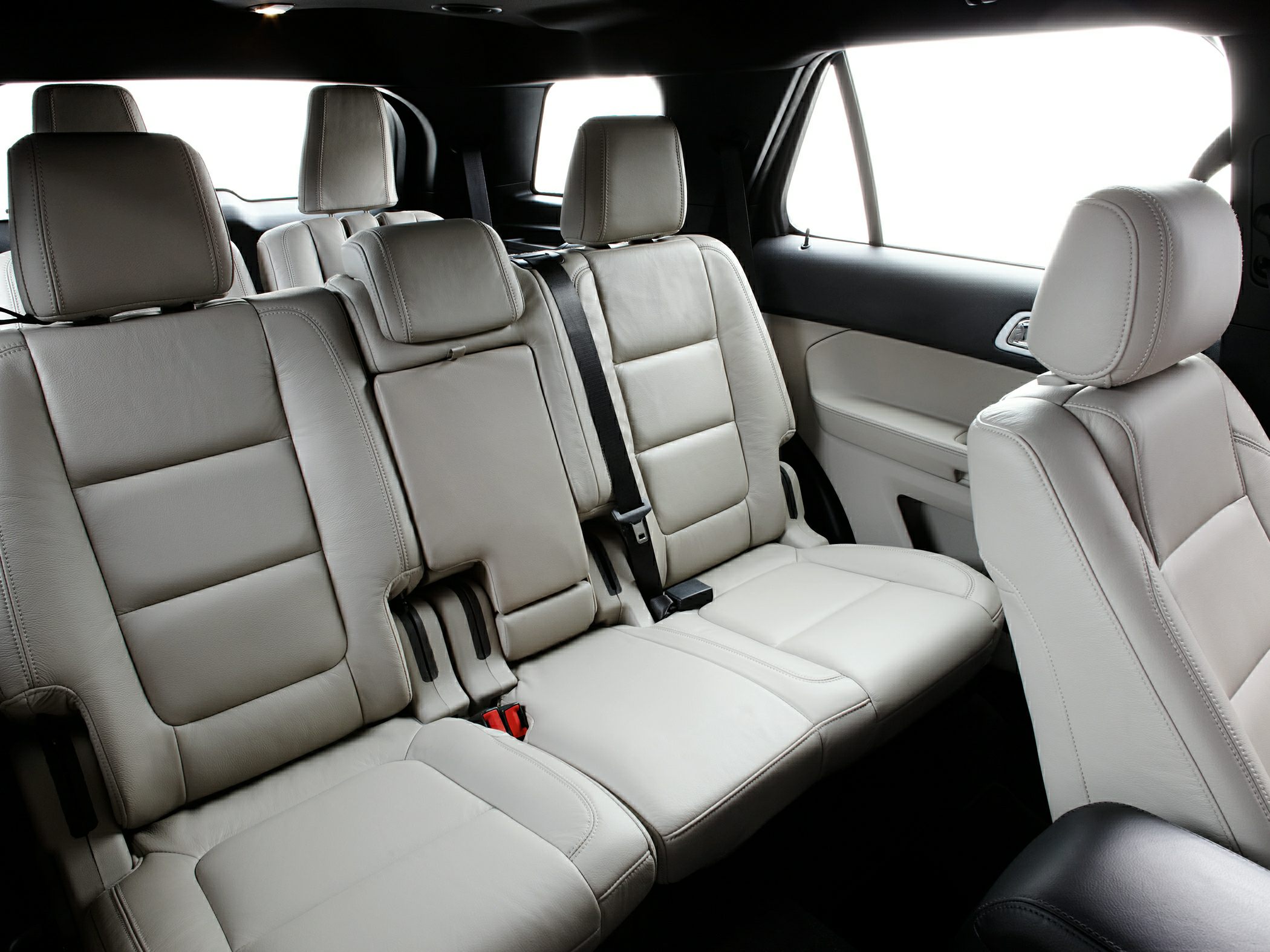 Spacious three-row leather seats with headrests and seatbelts inside an SUV