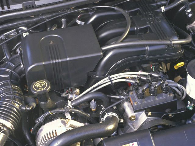 Close-up of engine bay with oil cap, hoses, and alternator.