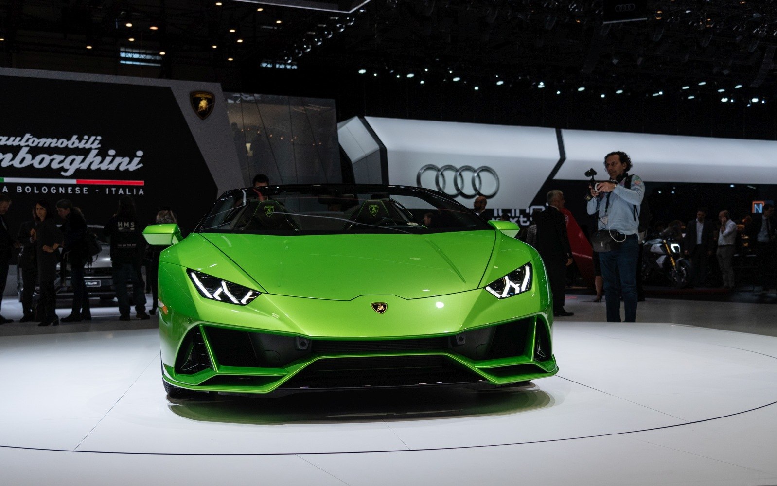 Front view of a vibrant green convertible supercar with angular headlights and aerodynamic design.